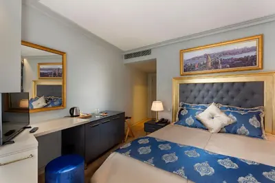 a bedroom with a bed with a desk and a mirror at Güner Business Hotel in Istanbul