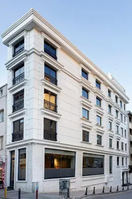 a large white building with windows on a street at Güner Business Hotel in Istanbul