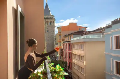 a woman standing on a balcony looking out of a window at Hotel Des Arts Galata in Istanbul