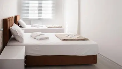 two beds in a white room with towels on them at Araz Suit in Burgaz