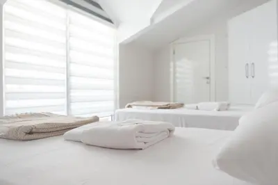 two beds in a white room with towels on them at Araz Suit in Burgaz