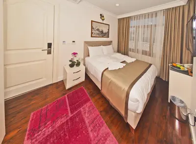 a bedroom with a large bed and a red rug at Nusretbey Hotel in Istanbul