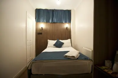 a small bedroom with a bed with a blue curtain at Genius Hotel Istanbul in Istanbul
