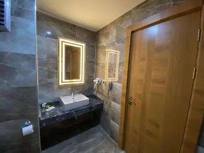 a bathroom with a sink and a wooden door at Green Prusa Hotel in Bursa