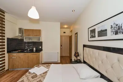 a bedroom with a white bed and a kitchen at Invictum Residence in Istanbul