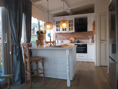 a kitchen with white cabinets and a kitchen island with two lights at The White Swan Suites Beyoglu in Istanbul