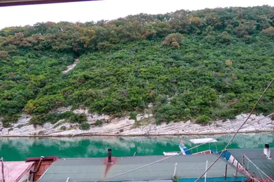 a boat in the water next to a mountain at Ağva Carpediem Otel in Agva