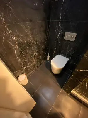 a bathroom with a toilet and a black marble wall at West Palace in Istanbul