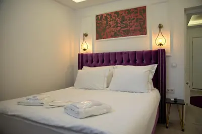 a bed with a purple headboard and two towels on it at Blue Mosque Suites 2 - Old City Sultanahmet in Istanbul