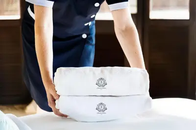 a woman holding two white towels on a table at İstanbul Terrace Hotel in Istanbul