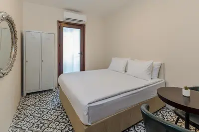 a white bed in a room with a table and a desk at Sanat Hostel Taksim in Istanbul