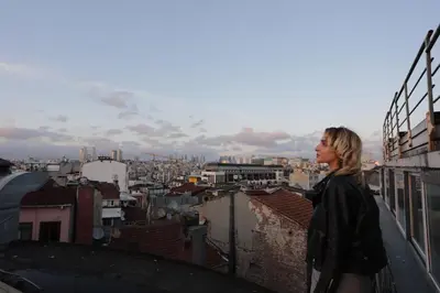 a woman standing on a roof looking at a city at Sanat Hostel Taksim in Istanbul