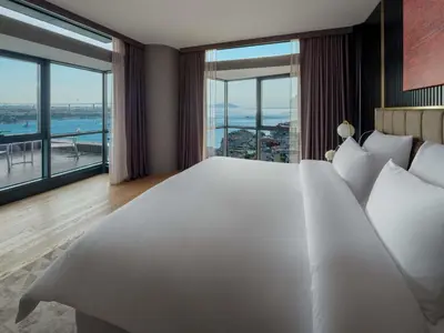 a large white bed in a room with large windows at Sofitel Istanbul Taksim in Istanbul