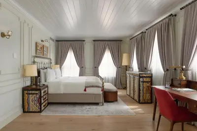 a bedroom with a bed and a desk and windows at Kocatas Mansions in Istanbul