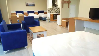 a living room with blue chairs and a table and a kitchen at SKYBLUE İSTANBUL HOTEL in Istanbul