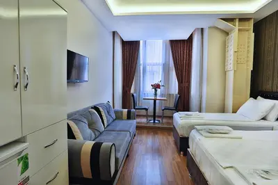 a hotel room with two beds and a couch at Gh Suites Taxim Hotel in Istanbul