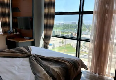 a bed in a room with a large window at Grand Rimedya Hotel Bursa in Panayır
