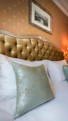a bed with a gold headboard and a green pillow at Hotel Gritti Pera & Spa in Istanbul