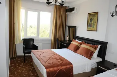 a bedroom with a bed and a chair and a window at Hotel Kuk in Istanbul