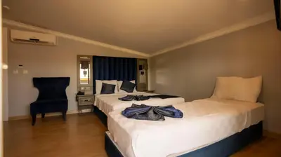 a hotel room with two beds and a chair at Farina Hotel By Cigno in Istanbul