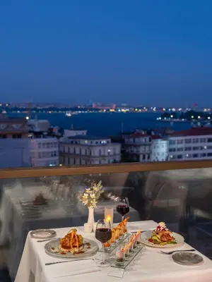 a table with plates of food and candles on it at Azzap Hotel Galata in Istanbul