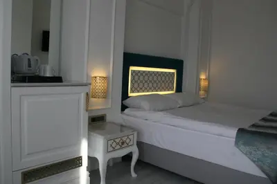 a white bedroom with a bed and a side table at Ligos in Istanbul