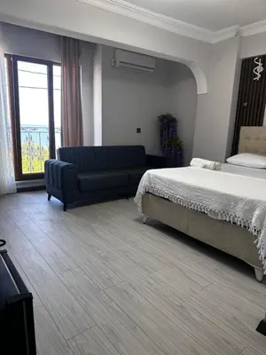 a bedroom with a bed and a couch and a window at KILIÇ MOTEL in Istanbul
