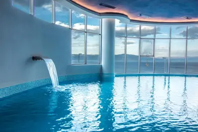 a swimming pool with a waterfall in a building with windows at BLUE MUDANYA HOTEL in Bursa