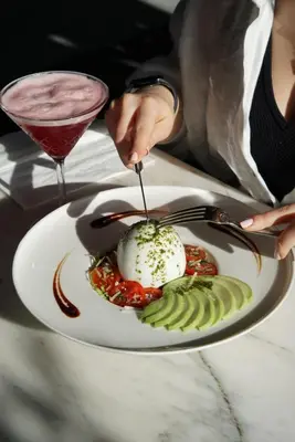 a woman eating a dessert on a plate with a drink at 39 Kalamış Marina Hotel & Restaurant in Istanbul