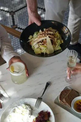 a person holding a pan of food on a table at 39 Kalamış Marina Hotel & Restaurant in Istanbul