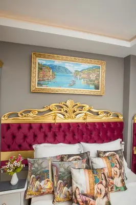 a bed with a gold headboard and a painting on the wall at Atlantis Royal Hotel in Istanbul