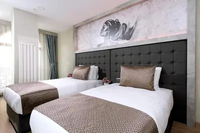 two beds in a hotel room with a painting on the wall at Four Sides Sisli in Istanbul