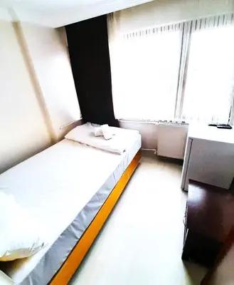 a bedroom with two beds and a desk and a window at Ozbekler Hotel-Old City in Istanbul