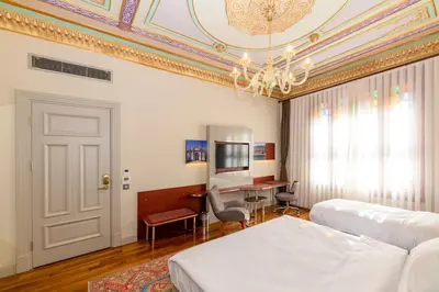 a bedroom with a bed and a desk and a chandelier at Blue Gilroy Hotel in Istanbul