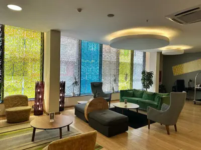 a lobby with a green couch and chairs and tables at Tempo Suites Airport in Istanbul