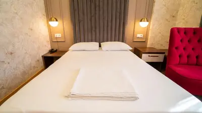 a bedroom with a white bed and a red chair at DYMAR HOTEL in Istanbul
