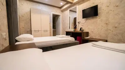 two beds in a room with a tv on the wall at DYMAR HOTEL in Istanbul