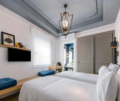 a white bedroom with two beds and a chandelier at The Soul Istanbul Hotel in Istanbul