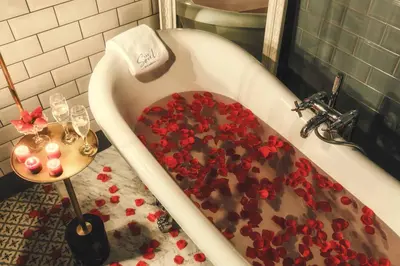 a bath tub filled with red flowers and wine glasses at The Soul Istanbul Hotel in Istanbul