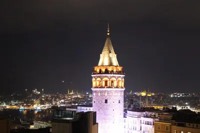 a tall tower with a steeple on top of a city at night at The Genoese Galata in Istanbul