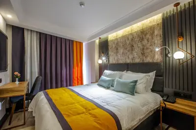 a hotel room with a bed with a desk and a bed sidx sidx at Kayhan City Hotel in Bursa