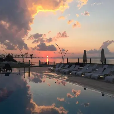 a pool with a reflection of the sunset in the water at Blue Pier Hotel in Kocaeli