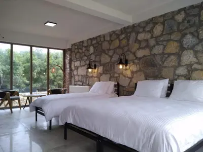 two beds in a room with a stone wall at İğneada Hotel Rezve in Kırklareli