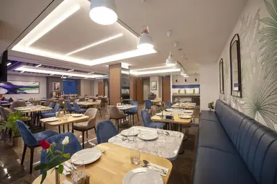 a restaurant with wooden tables and blue chairs at GRANBELLAHOTEL in Tekirdag