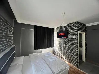 a bed in a room with a brick wall at Karaca Suite in Tuzla