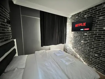 a bed in a bedroom with a brick wall at Karaca Suite in Tuzla