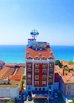 a red building with a tower on top of it next to the ocean at Kumburgaz Blue World Hotel in Buyukcekmece