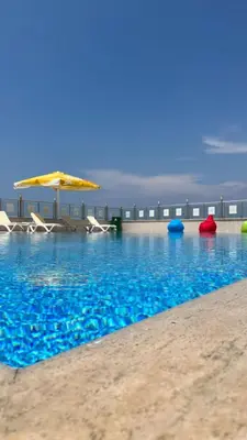 a swimming pool with chairs and an umbrella on the beach at DOUBLE ROYAL HOTEL in Kocaeli