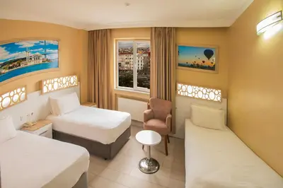 a hotel room with two beds and a chair at GRAND VATAN HOTEL in Istanbul