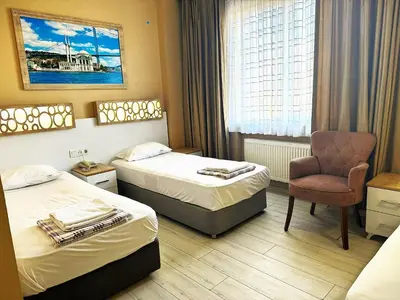 a hotel room with two beds and a chair at GRAND VATAN HOTEL in Istanbul
